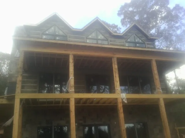 Dormers and porch framing on a large log home under construction — Roof Coating work by our crew in Clarkston