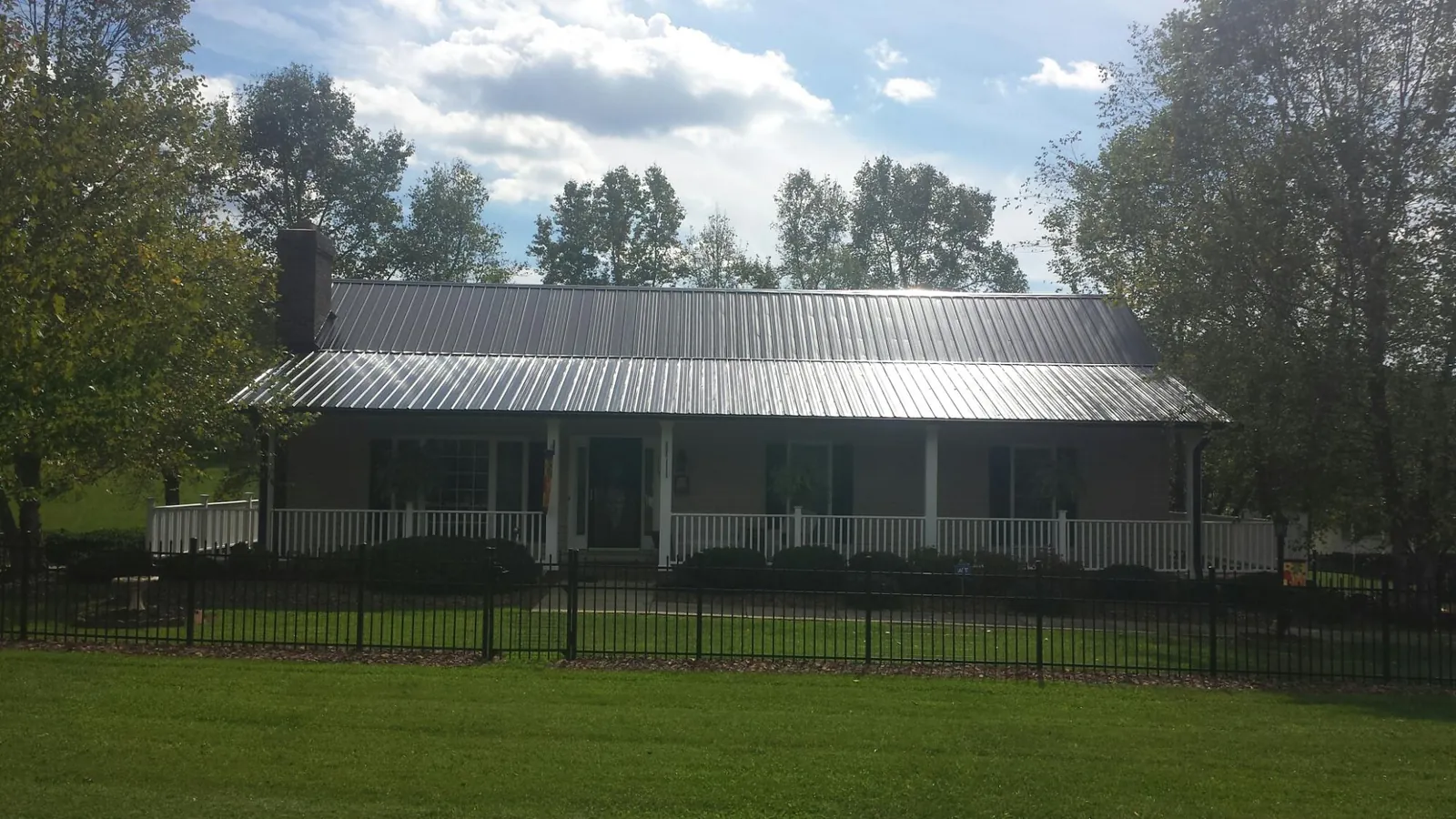 Gray metal roof on a brick ranch with a full width front porch — Gutter Guard Installation work by our crew in Clarkston