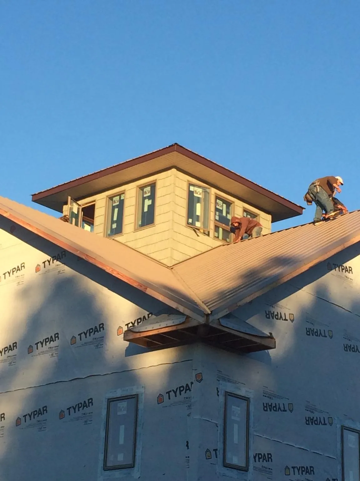 Roofers working around a rooftop cupola on a new metal roof at sunset — Roof Waterproofing in Clarkston by Roofing Brothers
